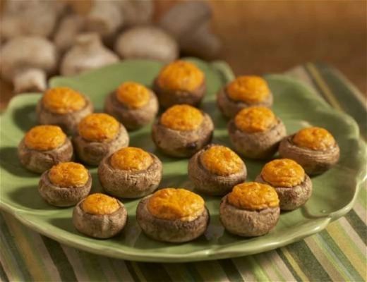 Stuffed mushrooms topped with cheese on a green plate.