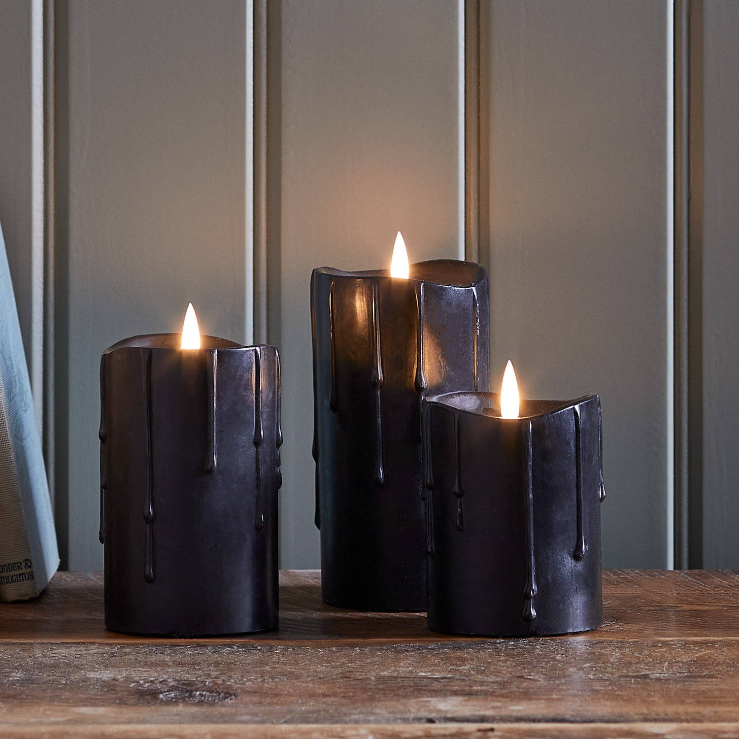Trio of three black dripping wax LED candles indoor