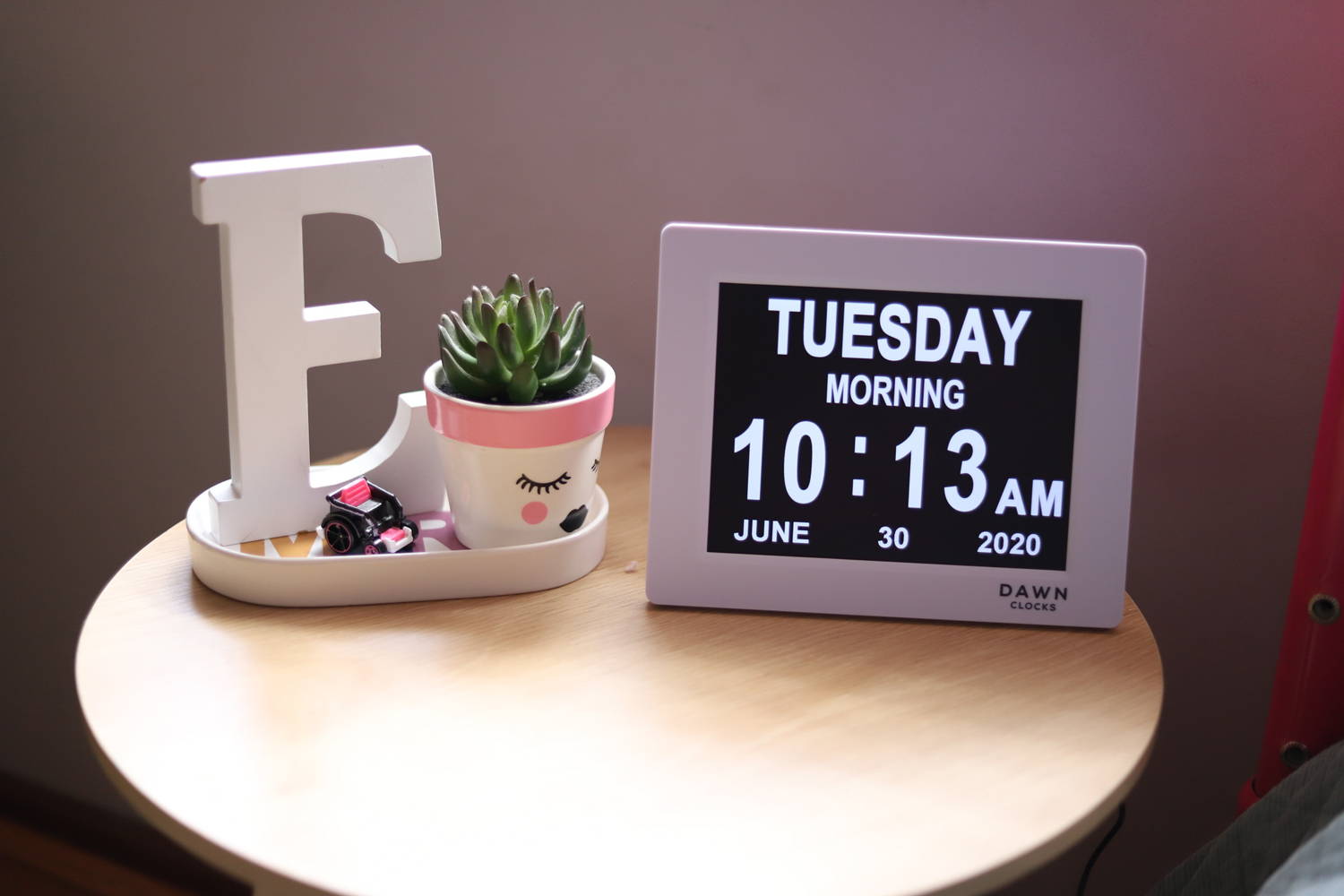 Dawn Clock sits on bedside table next to white "E" and cactus.