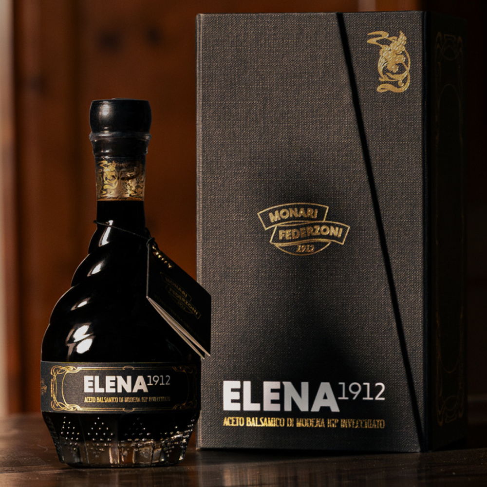 Bottle of Elena 1912 liquor next to its elegant black packaging.