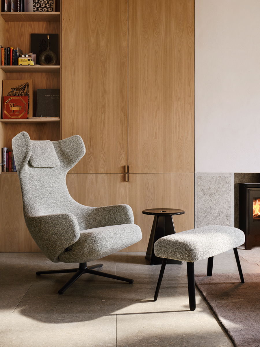 A modern gray Grand Repos armchair by Vitra beside a small black table in a cozy room.