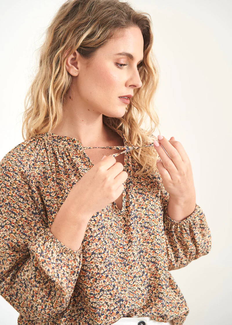 A model wearing a floral long sleeved blouse with neck ties