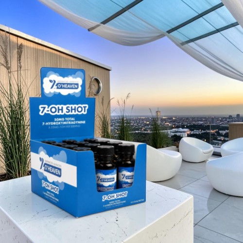 A display box of 7-OH Shot overlooking a city skyline at sunset.