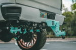 Close-up teal train horn kit and drop hitch on rear of Nick's white Silverado photo 4