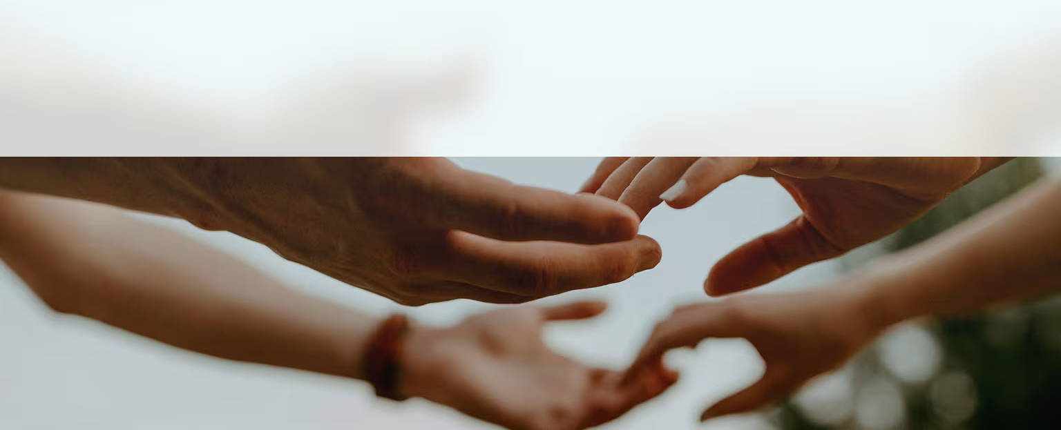 Hands reaching out to each other against a soft, blurred background.
