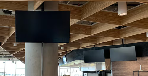 Several blank screens hanging from a wooden ceiling in a modern interior.