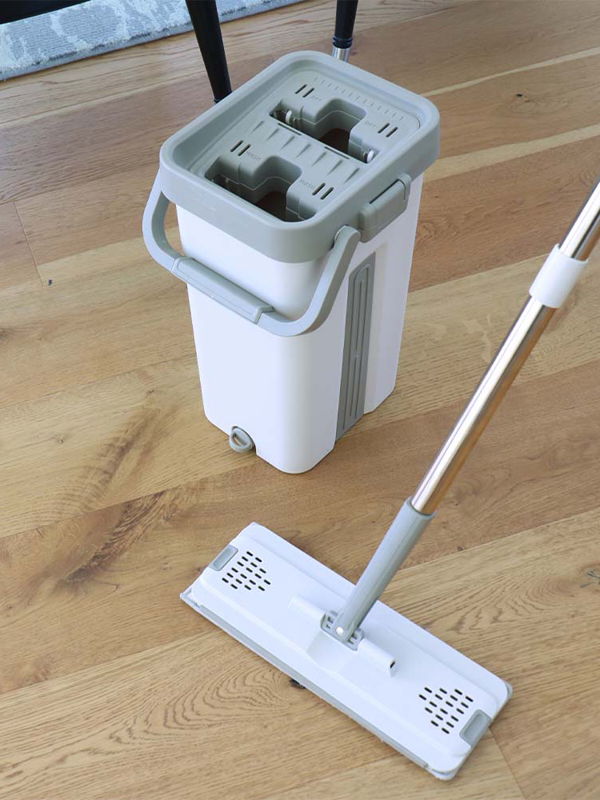 A mop and bucket set on a wooden floor.