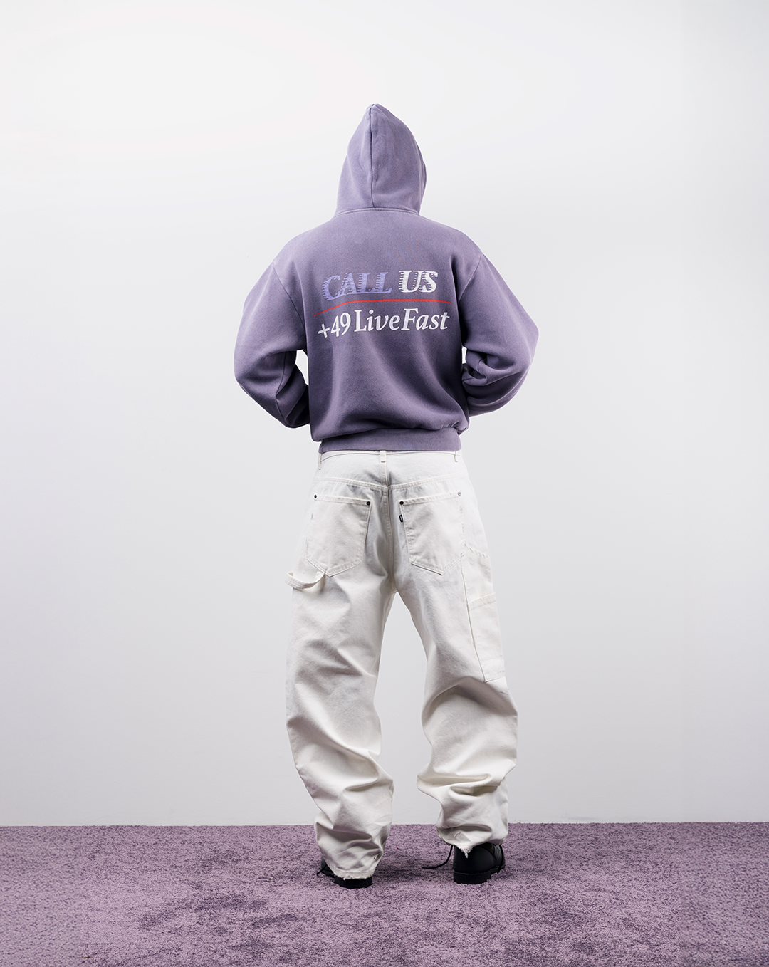 Person wearing a purple hoodie and white pants, facing away from the camera.