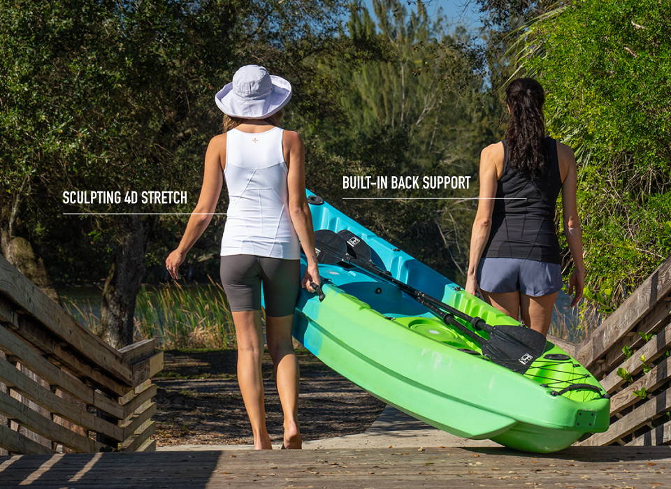 Two women wearing the Lower Back Support Tank while carrying a kayak