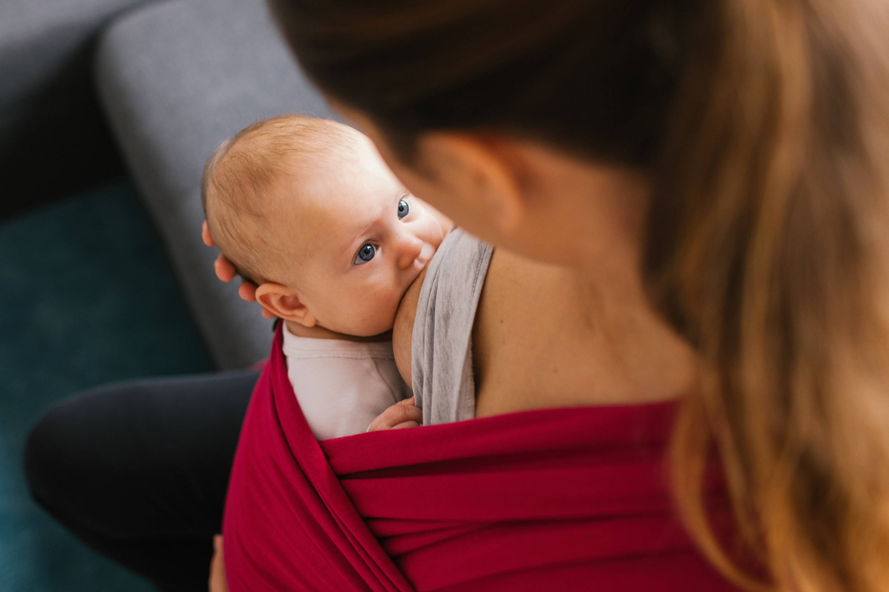 Baby in eye contact with mom while breastfeeding in a Sangria pink colored cotton wrap