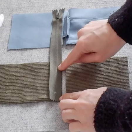 hand showing where to sew when attaching the zipper to the different pieces of fabric 