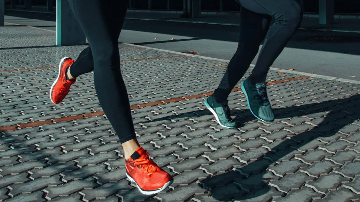 Male and female running on brick