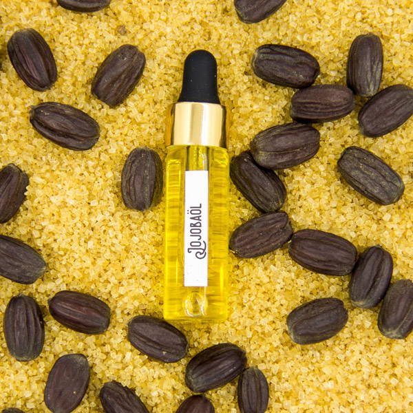 Jojoba oil and jojoba seeds against a sugar background