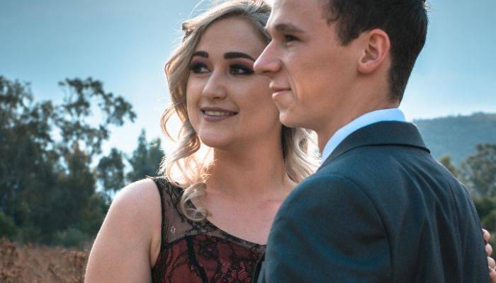 Teenage couple in formal attire posing outside