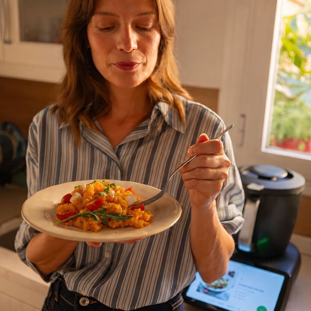 Woman holding a plate of food, enjoying a meal in a kitchen.