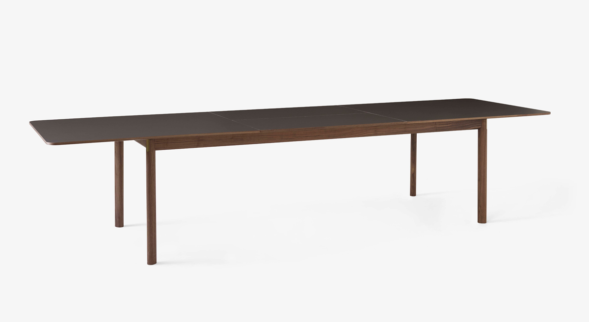 A long wooden dining table with minimalistic design and slender legs.
