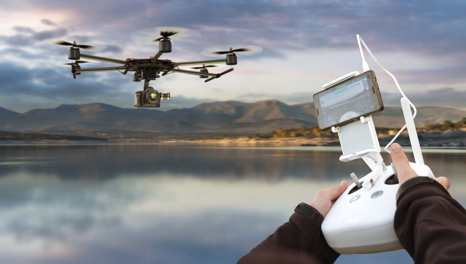 Person controlling a drone over a reflective water surface.
