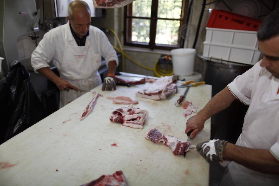 Two artisan butchers prepare Pancetta