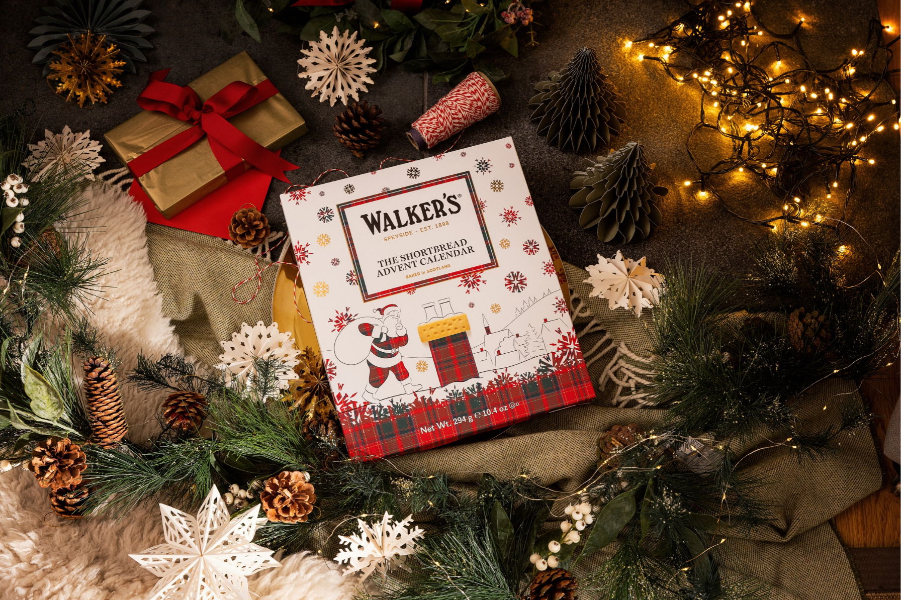 Christmas-themed arrangement with gifts, decorations, and a Walker's shortbread box.
