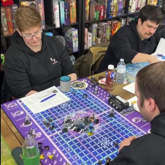 People playing a tabletop game at a table with game pieces and notes at Nexus Kingston.