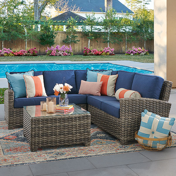 Outdoor seating area with a sectional sofa, coffee table, and decorative pillows.