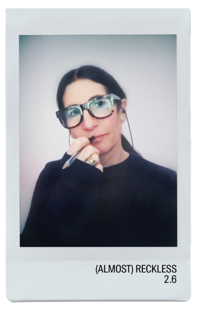 A woman with glasses holding a pen, looking thoughtful.