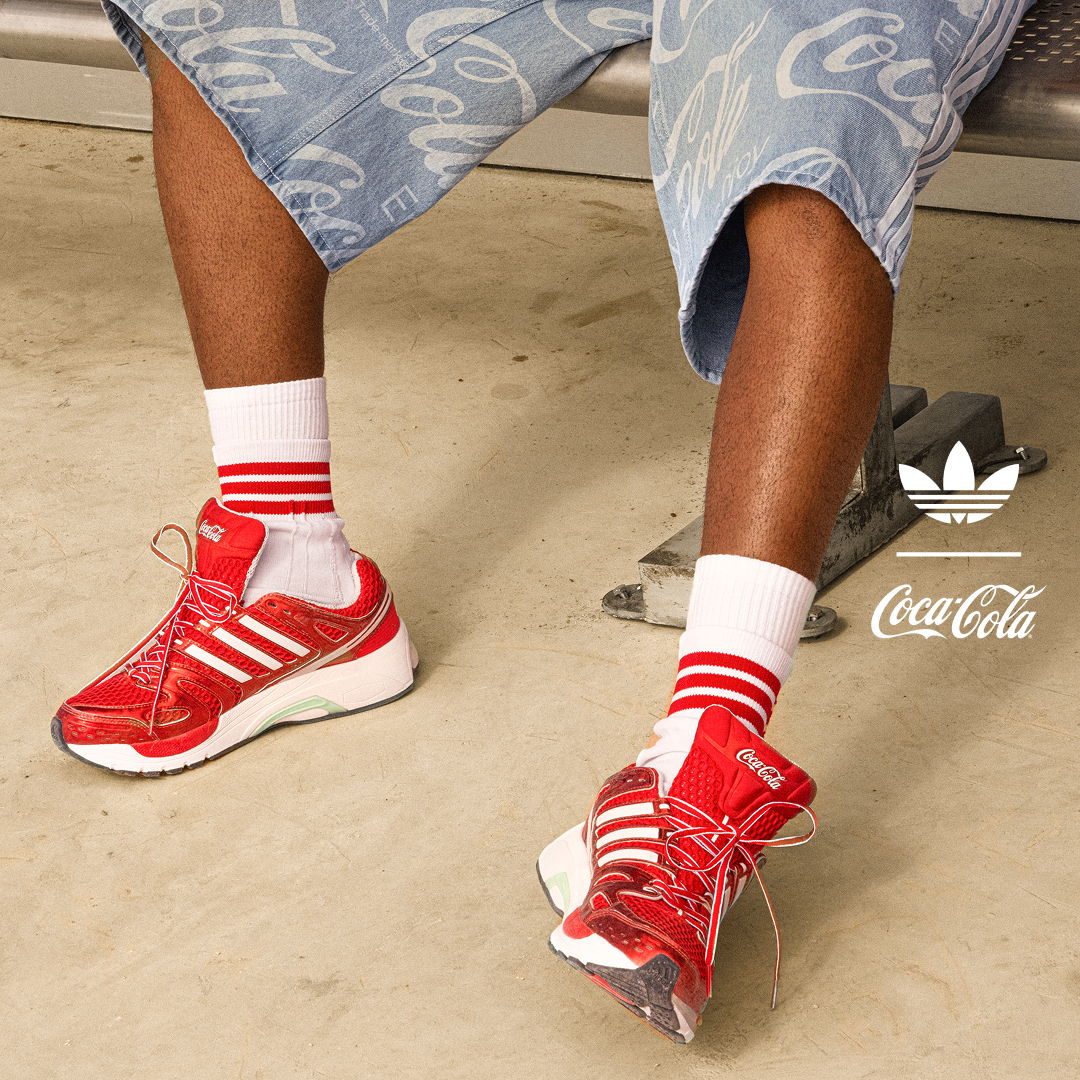 Red sneakers with white stripes, blue shorts, and Coca-Cola branding.