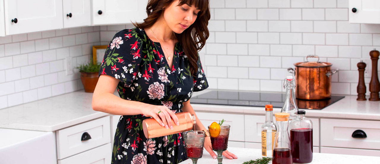 Woman pouring Cranberry Mocktail into vintage glass