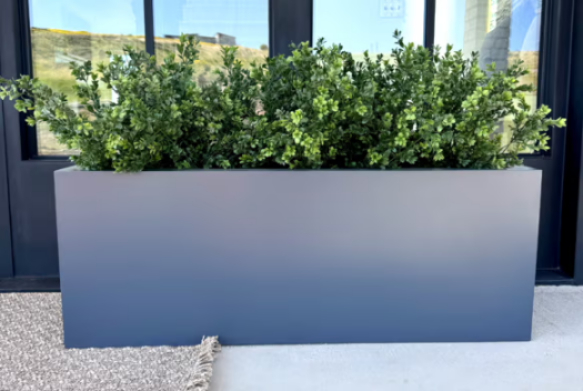 A modern planter box with lush greenery inside.