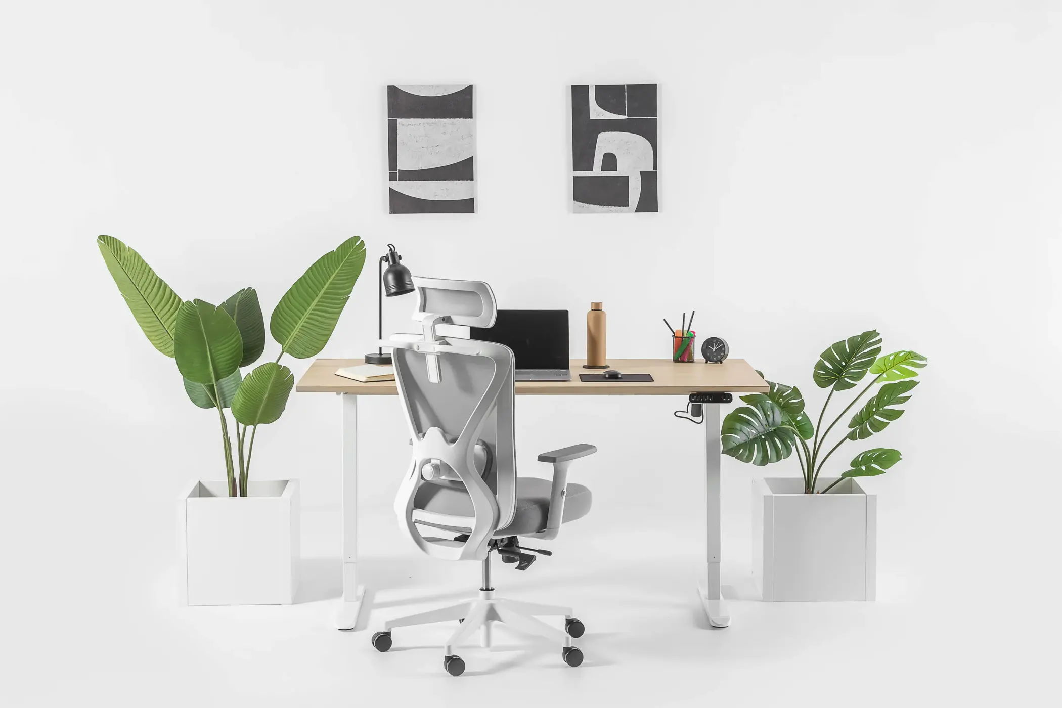 Een wit bureau met een computer en een bureaustoel, geschikt voor zowel zittend als staand werken.