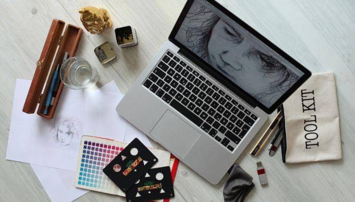 Top of desk view with a laptop and art supplies