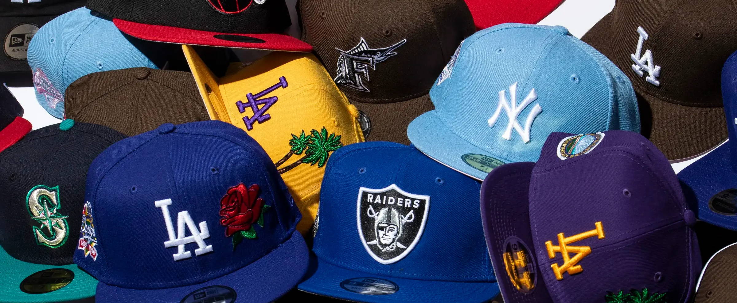 several colors and styles of new era caps scattered