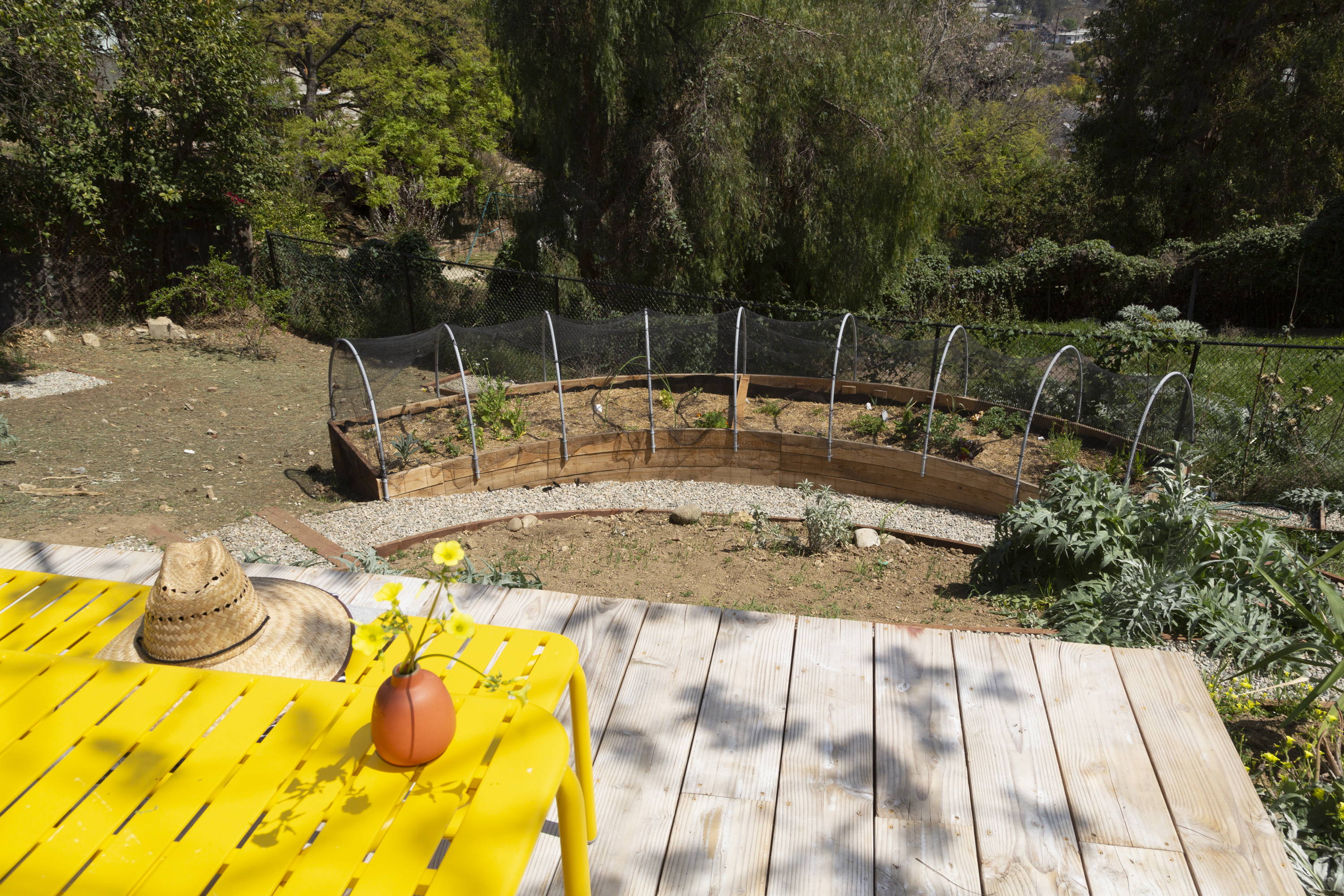 View from back porch with yellow table and bench and vegetable garden