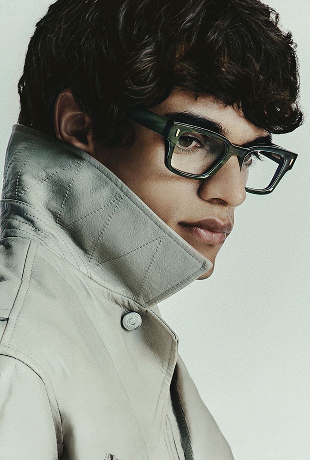 Young man in stylish glasses wearing a light-colored jacket.