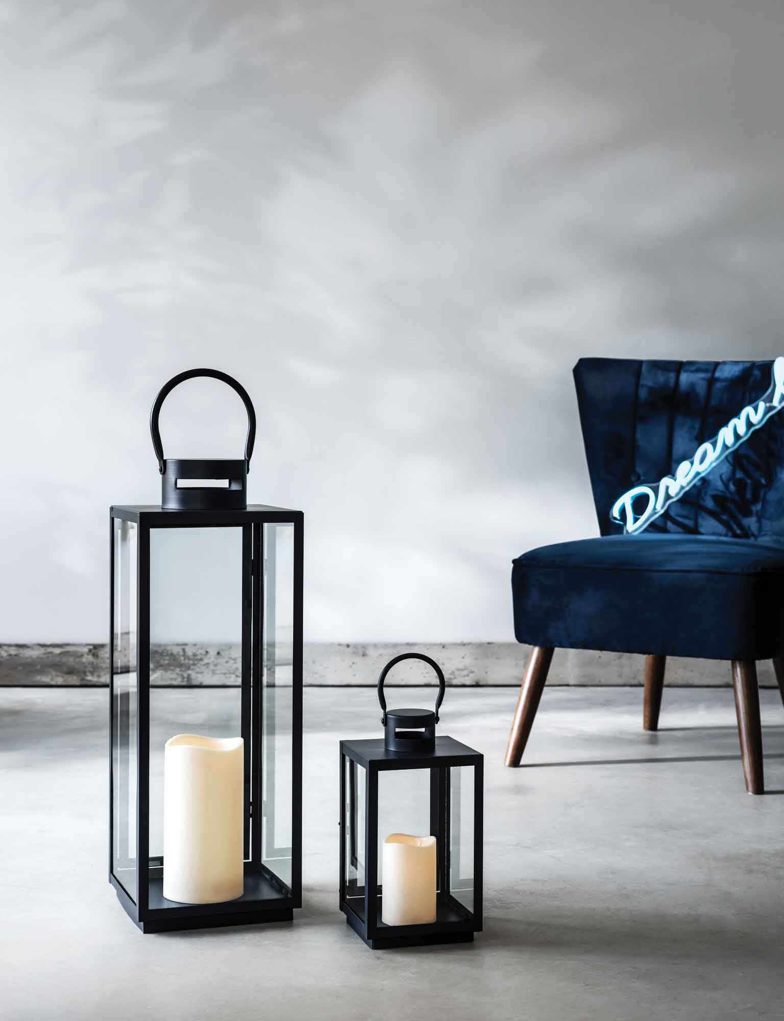 2 black lanterns with a blue chair behind with a 'dream big' neon light.
