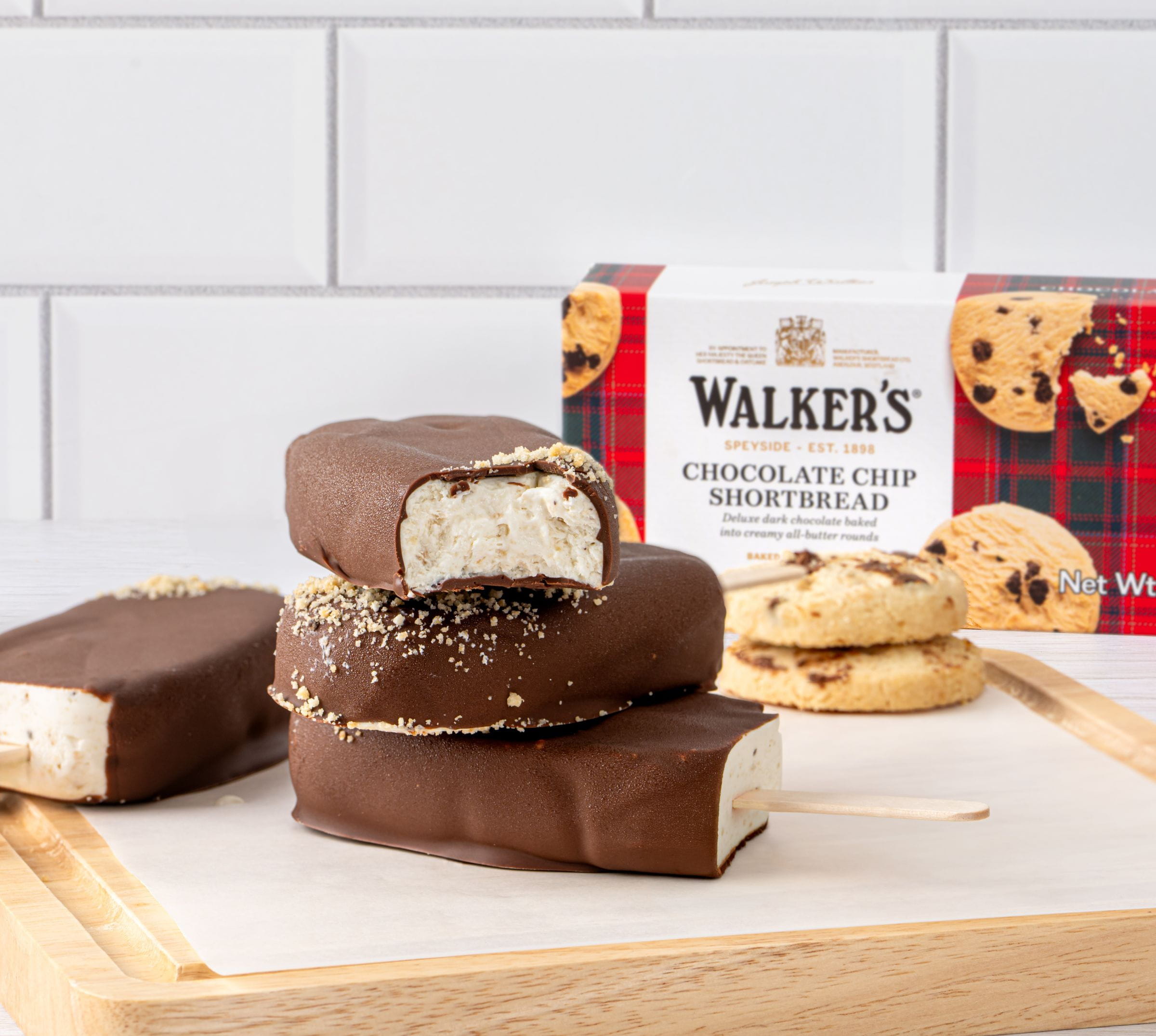Chocolate-covered treats on a wooden tray with cookies and packaging in the background.