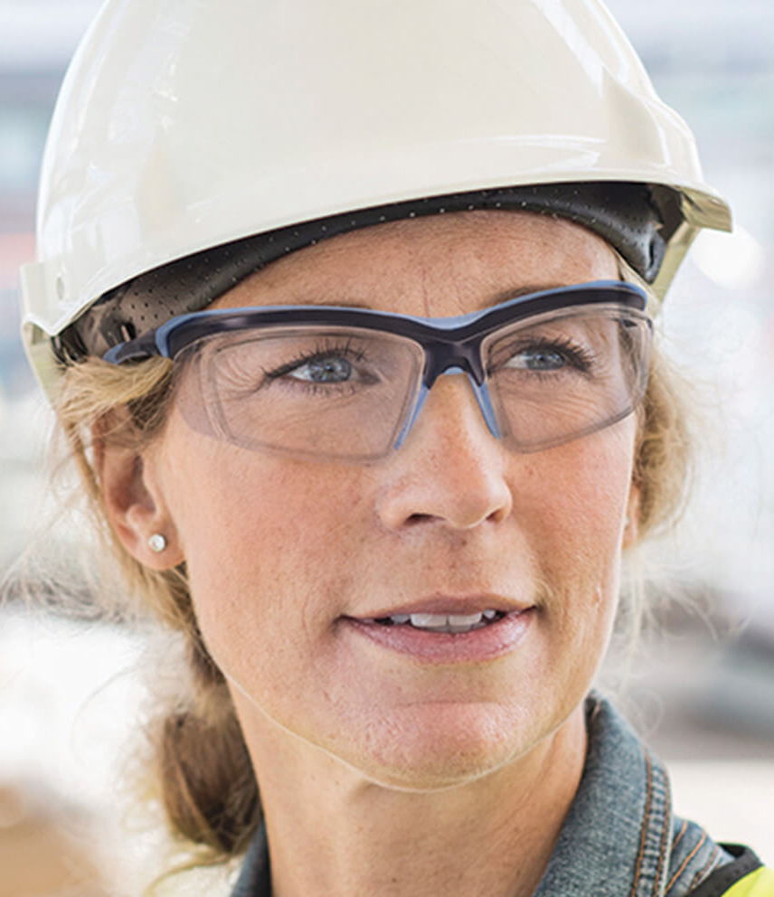 Woman wearing a hard hat and safety glasses at a construction site.