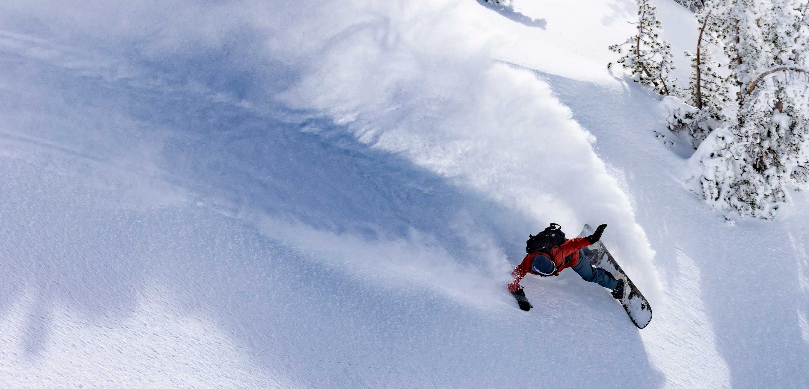 Person snowboarding on fresh powder snow in a mountainous landscape.