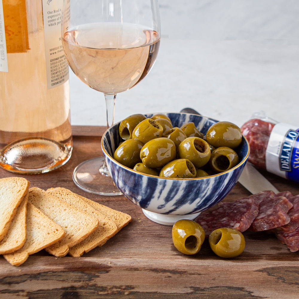 Olives, salami and crostini on a wood table with a bottle and glass of wine
