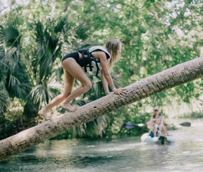 Girl climbing tree over a spring