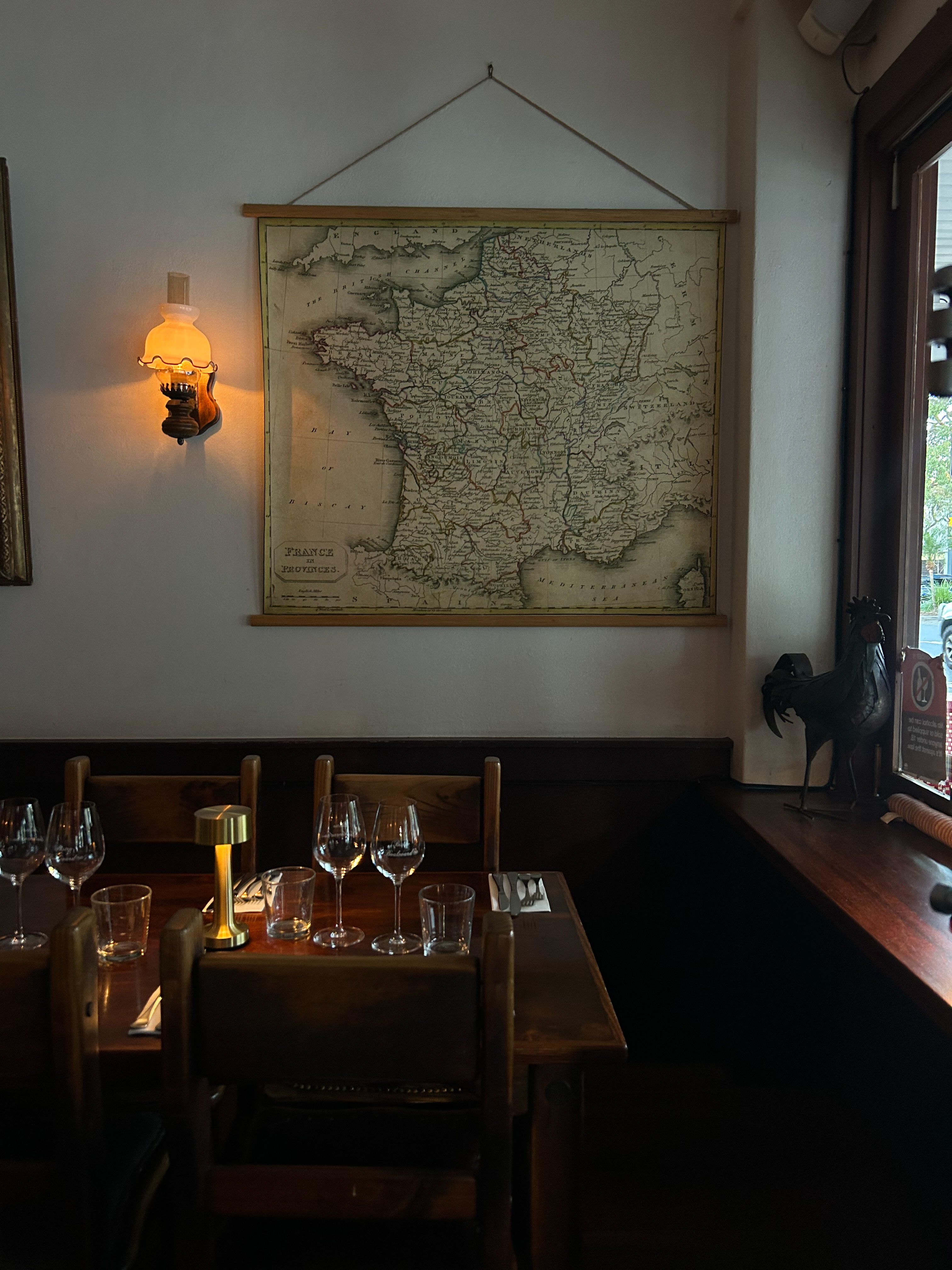 An inside view of restaurant Bistro Boulevard, the light is moody and there is a world map and sconce hanging on the wall.