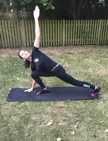 A woman in KYMIRA gear in mid-hip stretch. 