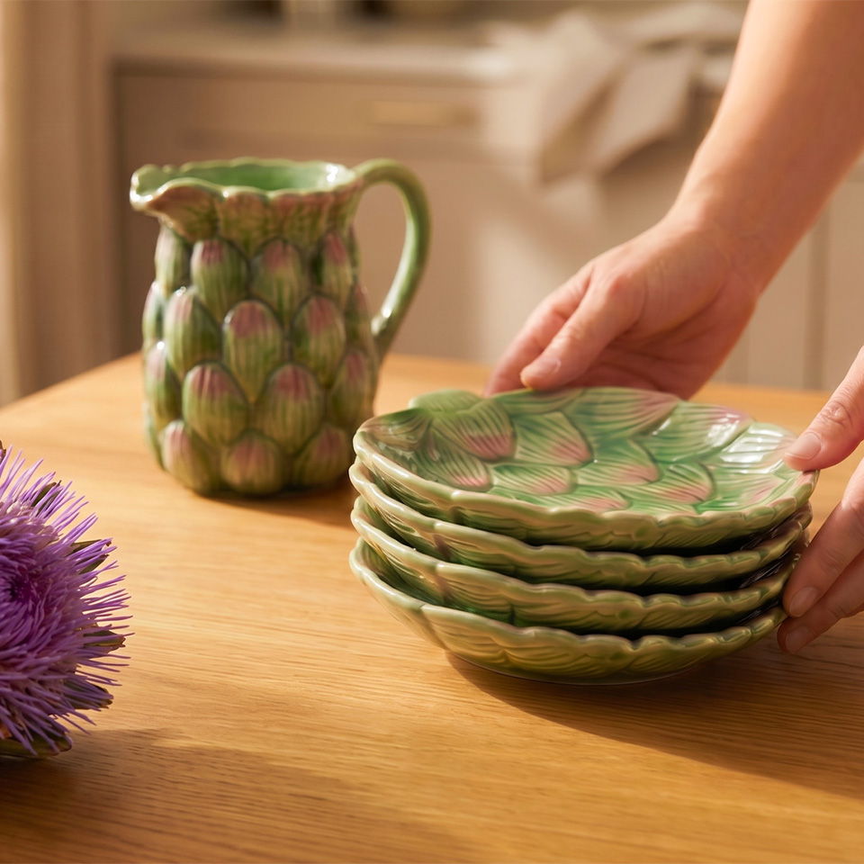 A person arranging green artichoke-shaped plates beside a pitcher on a table.