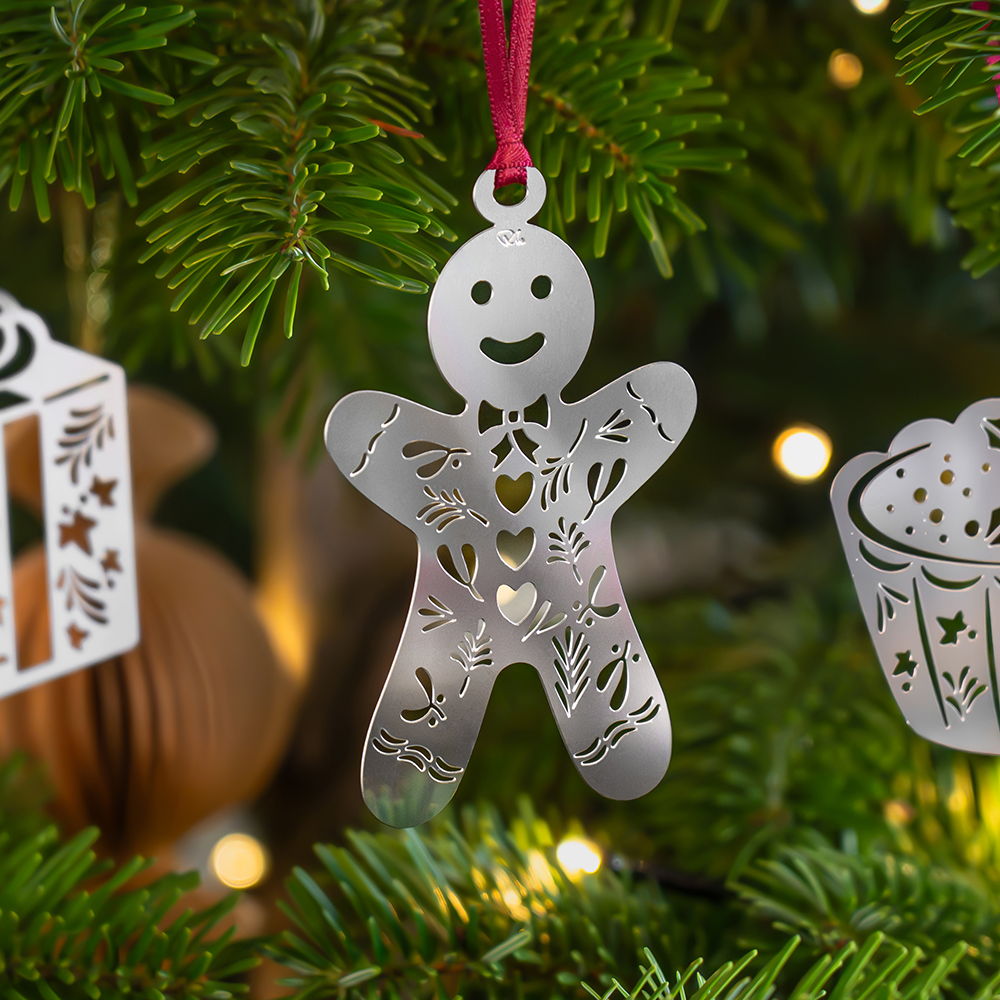 Gingerbread man ornament hanging on a Christmas tree.