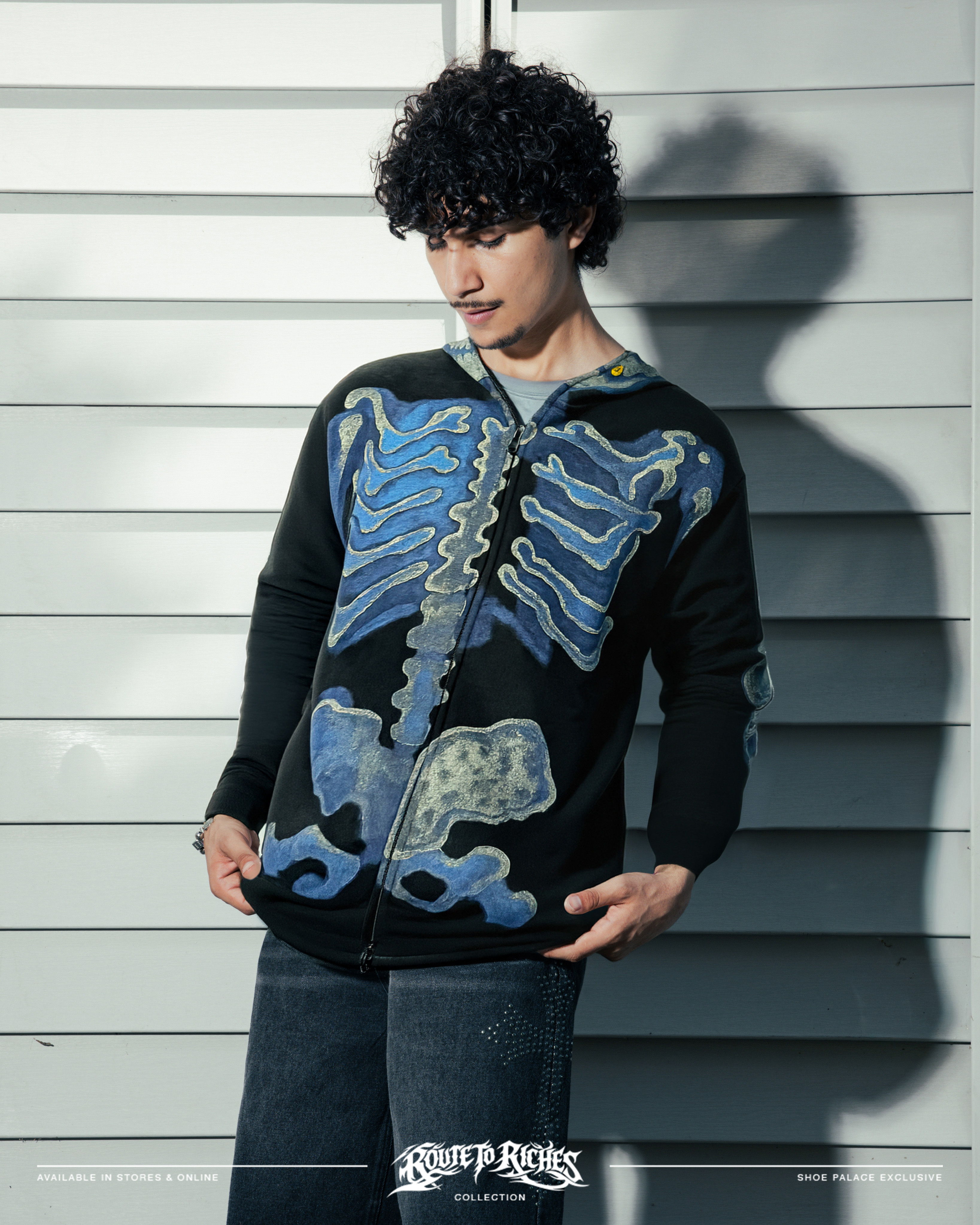 Person wearing a skeleton-patterned sweater against a wooden background.