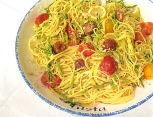 A bowl of spaghetti with cherry tomatoes and herbs.