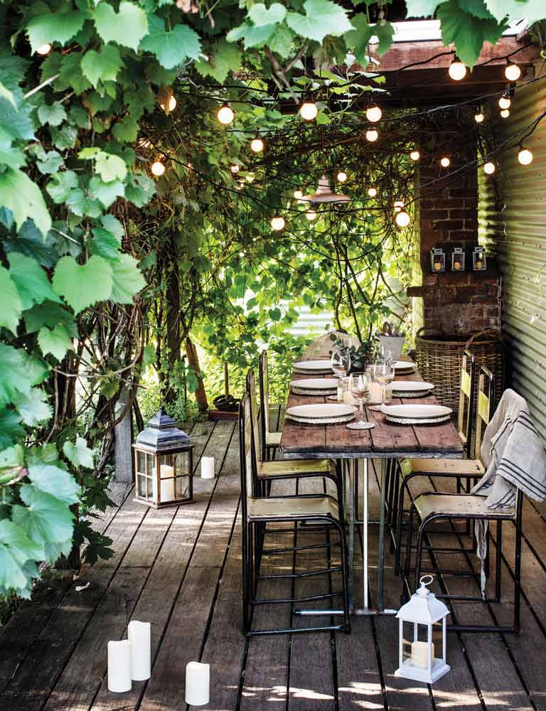 An outdoor dining area with candles, plants, festoons and lanterns.