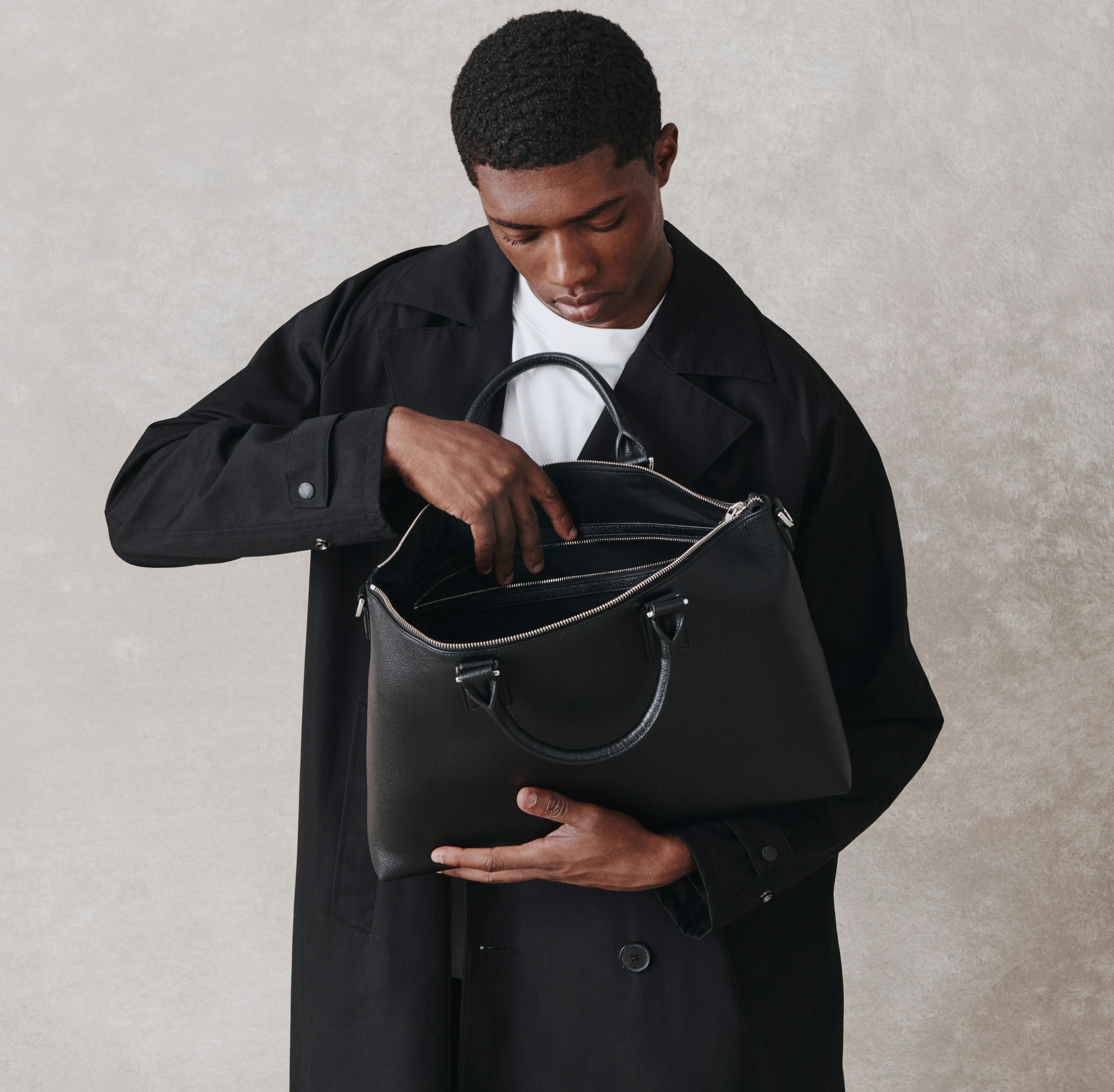 Person in a black coat examining contents of a black handbag.