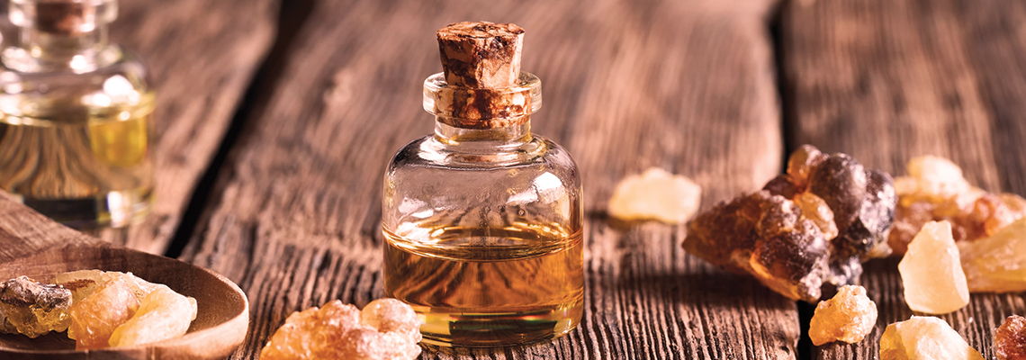 Glass bottle with cork, surrounded by resin pieces on a wooden surface.