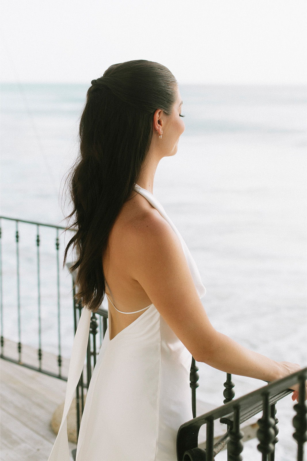 Woman in white dress gazing at the ocean.